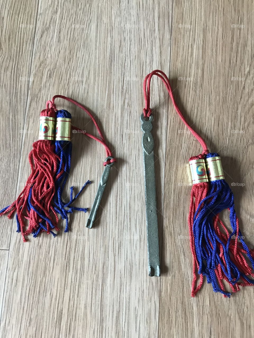 A drawers keys which is made from metal with a beautiful red and blue thread design. 