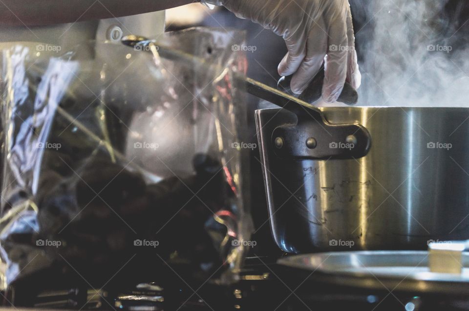 Chef hands cooking over steaming pot on stove 