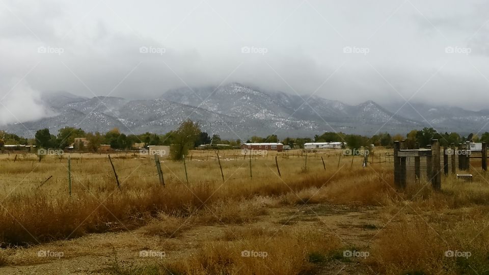 view of snow storm over mountain from field