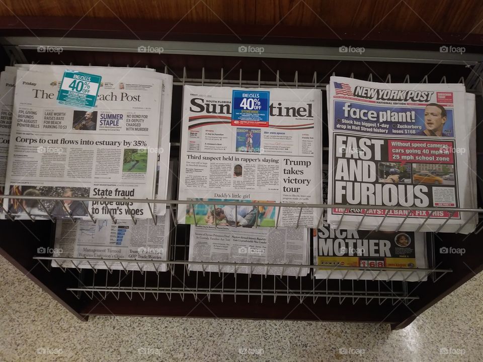 The Palm Beach Post is seen amidst the Sun-Sentinel and New York Post on a newsstand in West Palm Beach, Florida, United States.