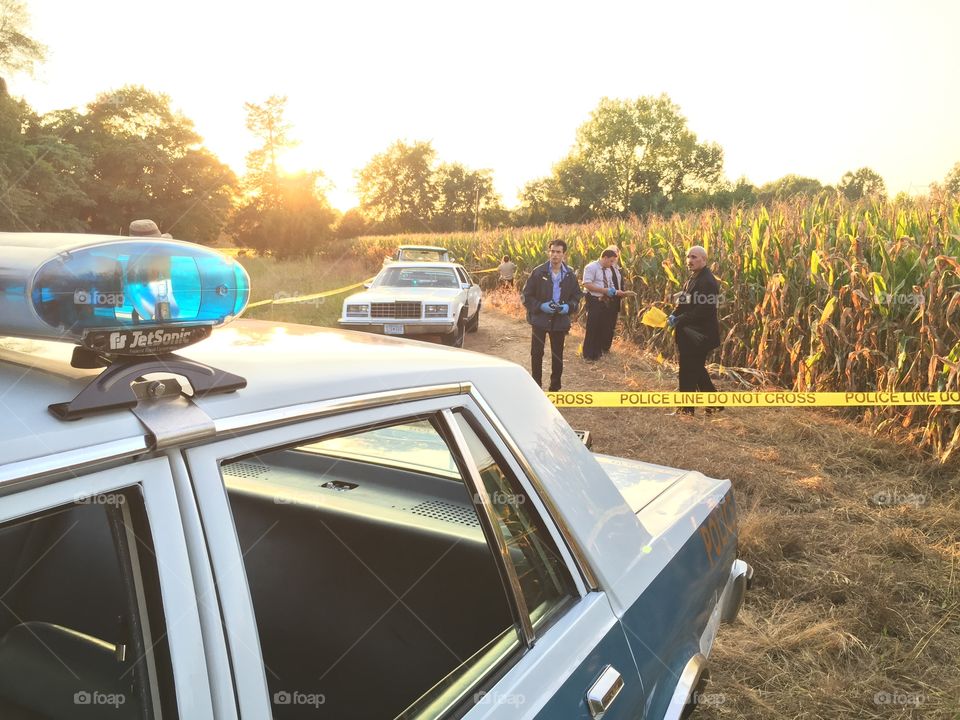 Police in the 1980’s searching for clues left behind the seen of a murder next to a cornfield. 