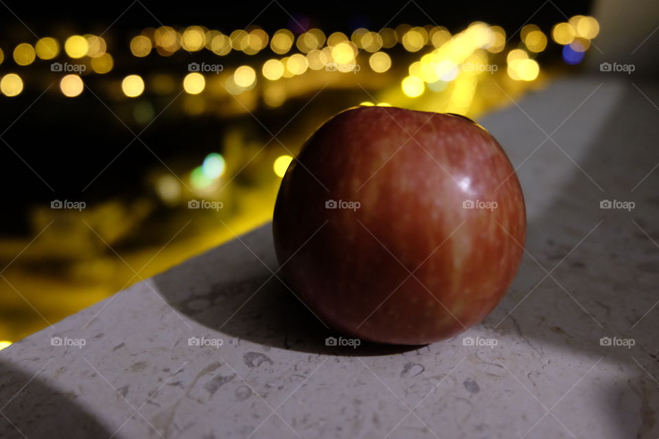 An apple on the edge of a window. 