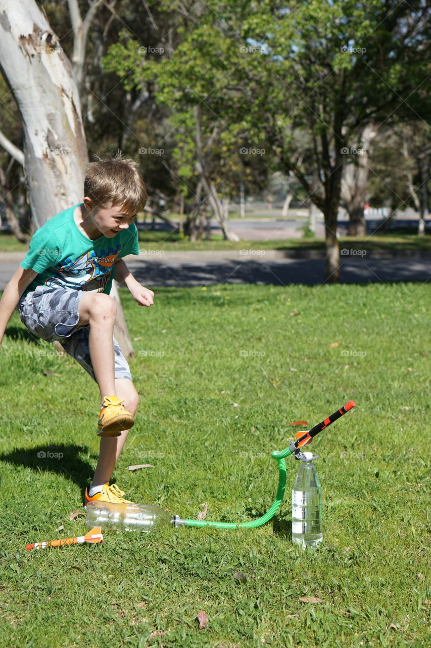 Rocketry. A boy about to step on a bottle to fire an air propelled rocket in the park