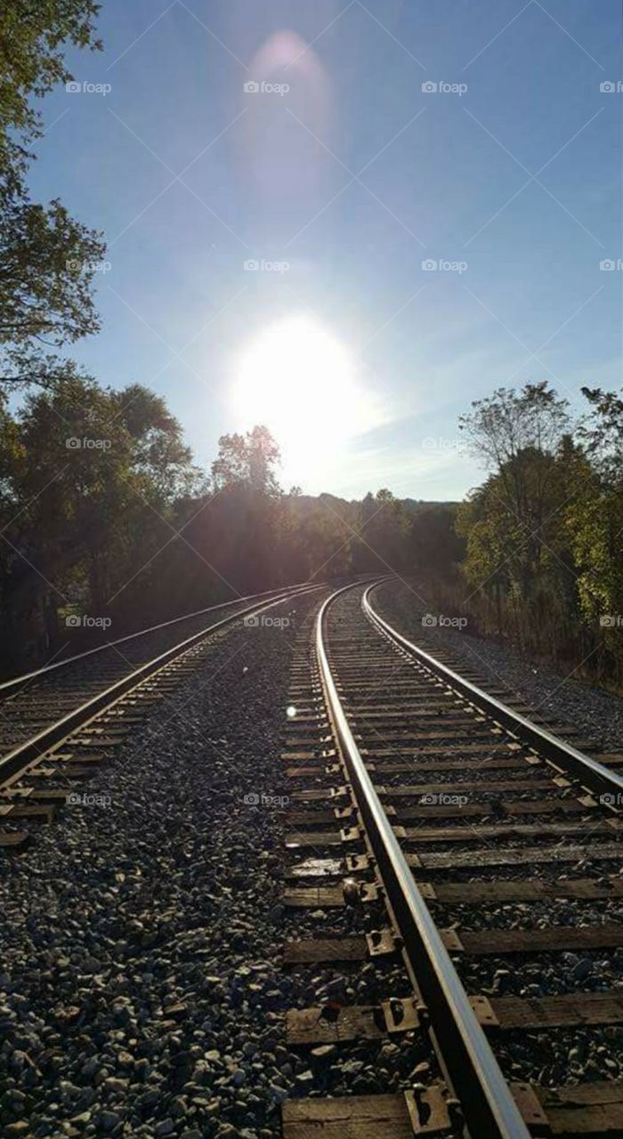 the sun sets by the railroad tracks.