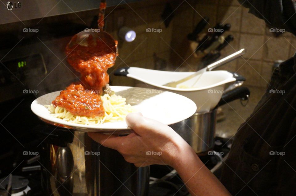 Pouring red sauce on pasta