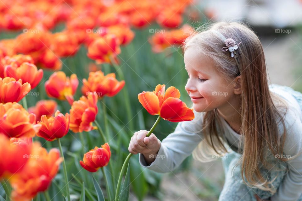 Girl sniffing tulip flower on field 