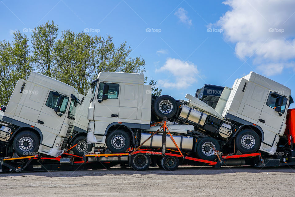 brand new trucks on a carrier truck, that delivers them to customers