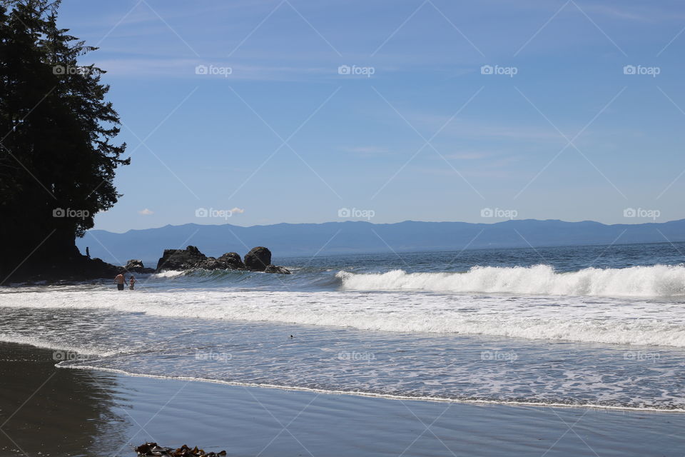 Big waves crash on the shore of wide o beach and people cooling in shallow water