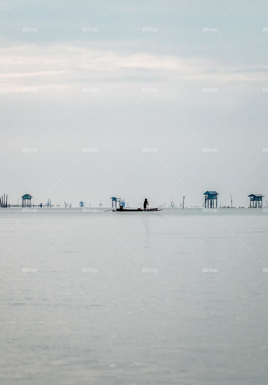 Silhouette of local  fisherman on his boat to work in sea scape