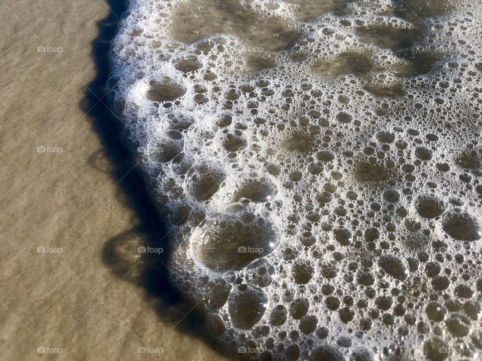 Closeup of ocean waves on sunny sand beach 