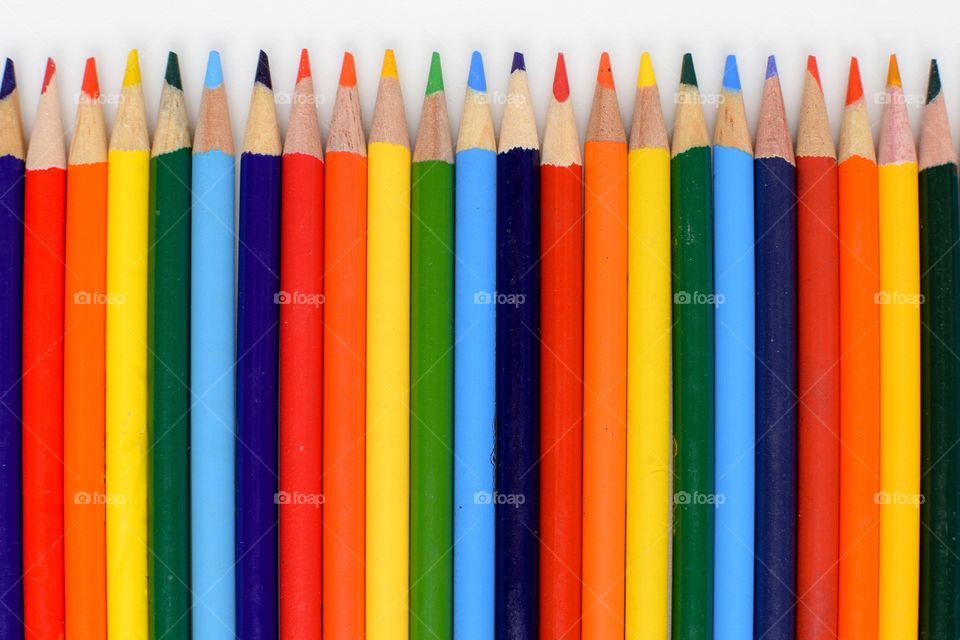 Arrangement of colored pencils over white background