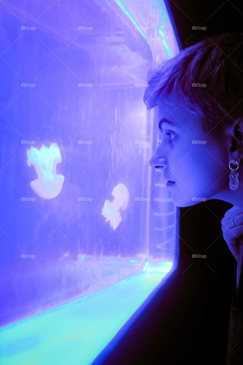 Beautiful Short Hair Girl watching a jellyfish tank, at a Brazilian Aquarium. Beautiful Purple Lighting.
