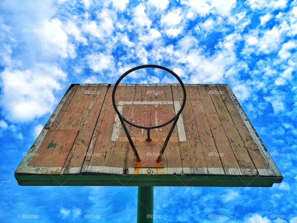 Old yard basketball ring against the blue sky.