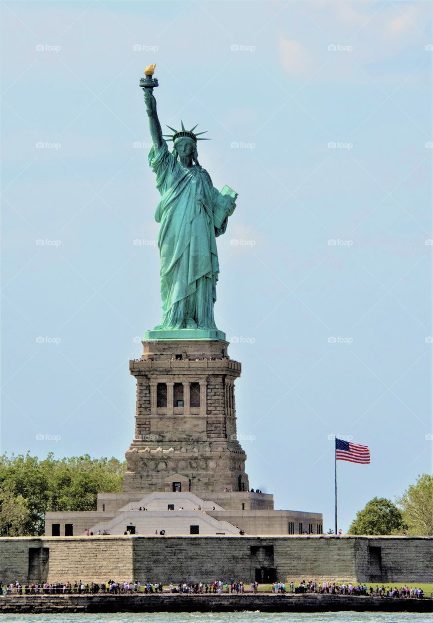 Statue of Liberty with the American flag flying beside it 