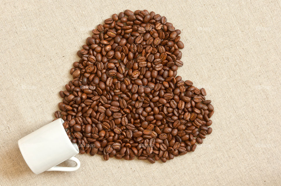 Heart shaped coffee beans spilled out of coffee cup