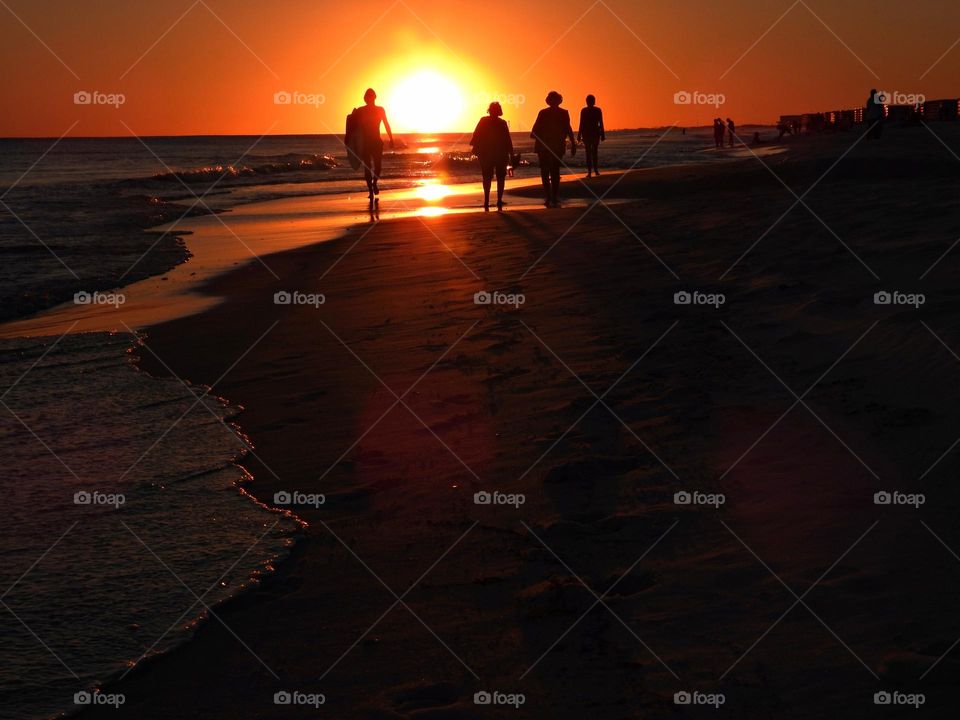 Watching the sunset, gulf of mexico - people in silhouette watching a brilliant sunset over the water of the Gulf of Mexico beach in December