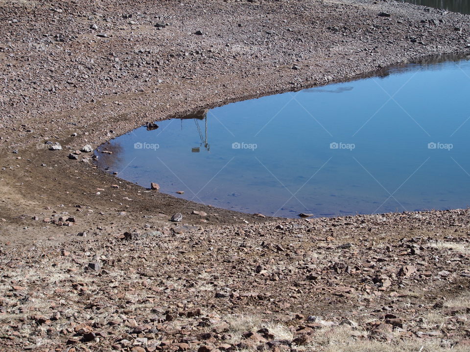 Reflections in the calm waters of Ochoco Reservoir along the rocky shores in Central Oregon on a sunny day 