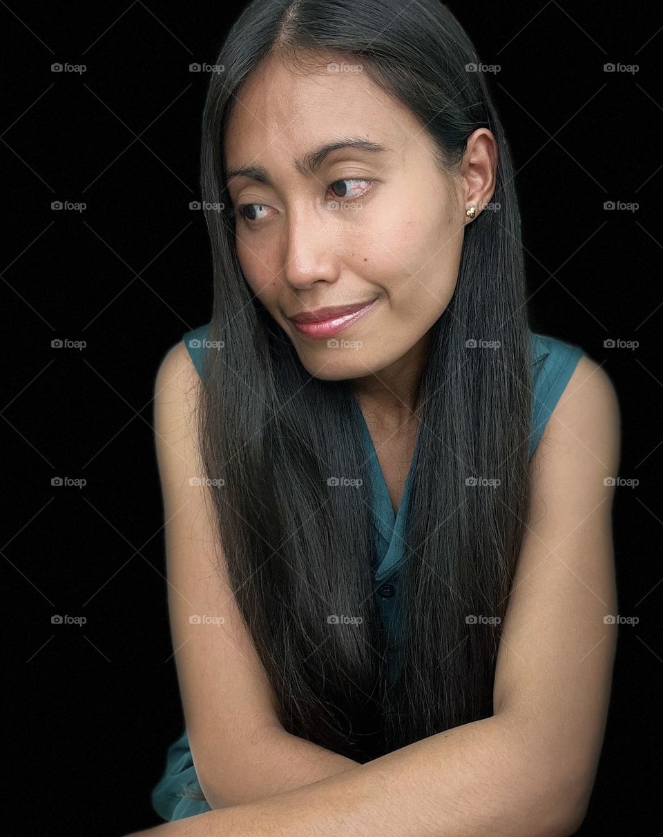 Portrait of young adult woman with long hair and black background.