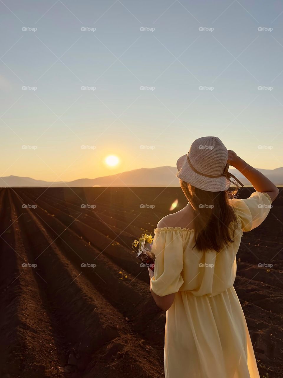 girl in a yellow dress at sunset in a field