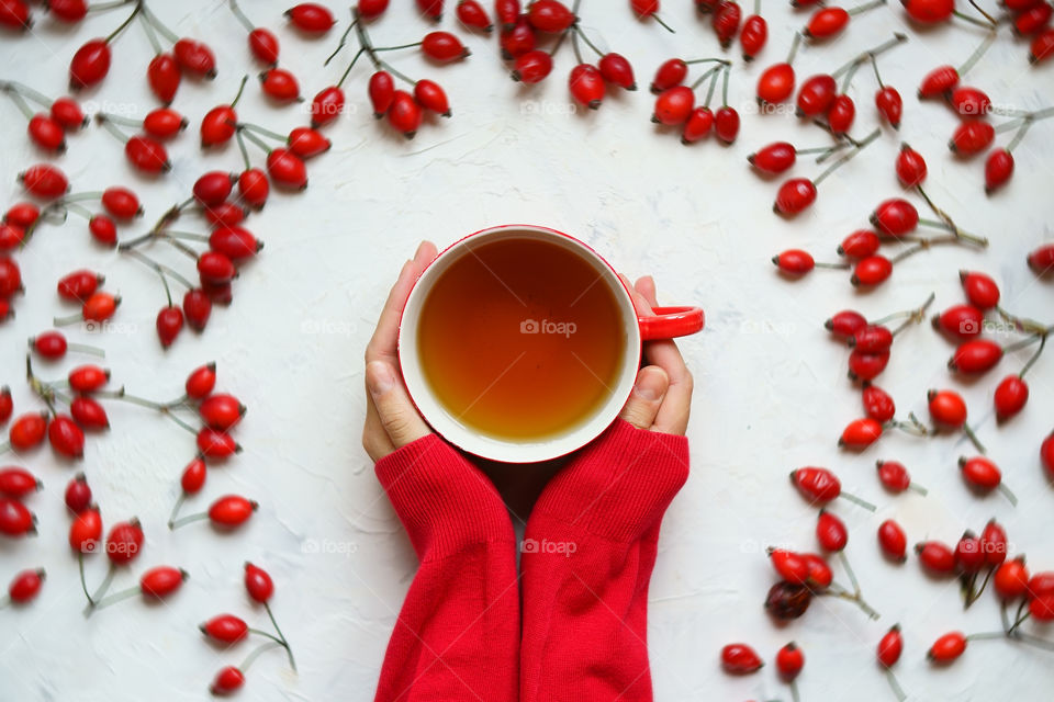 Girl's hands holding cup of hot herbal tea, top view.