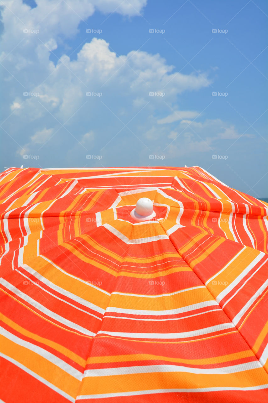 Orange beach umbrella against a blue sky. Perfect for cover art.
