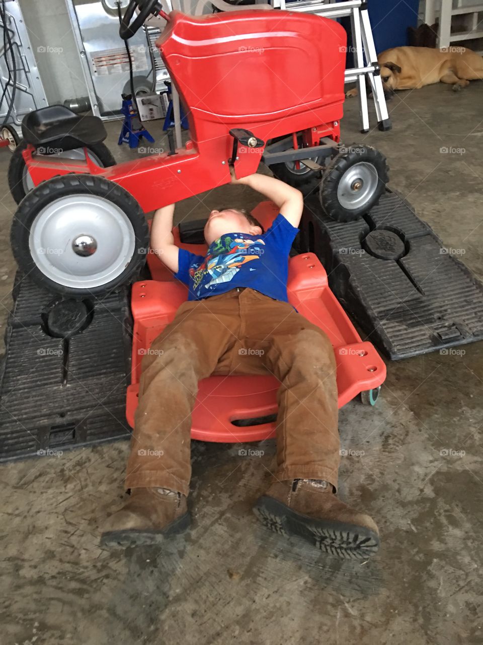 Young boy works on his toy tractor