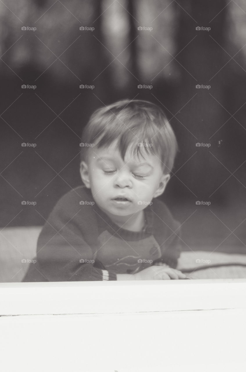 Boy pressing his nose on glass window