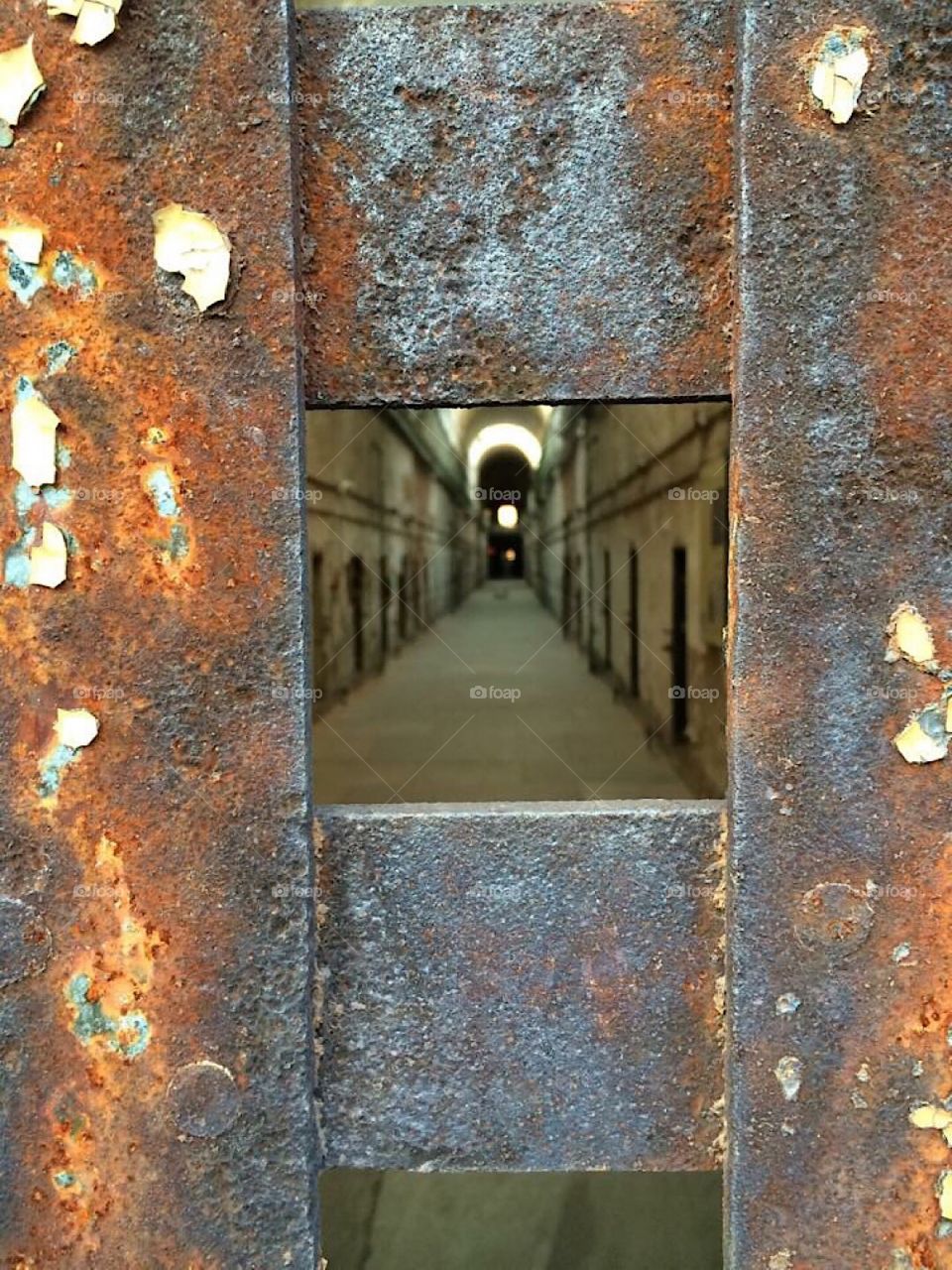 View through a metal barred door peering into the main cell block hall at Eastern State Penitentiary located in Philadelphia PA. Known for reported hauntings and the infamous Al Capone. 