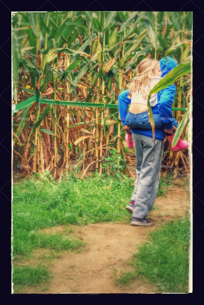 Piggy Back Ride. Big brother giving his little sister a piggy back ride through the corn maze.