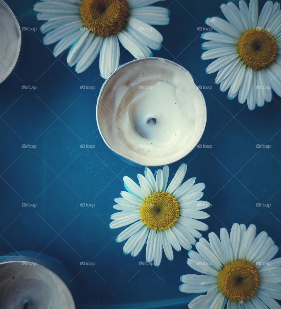 Daisy flowers and candles in blue water