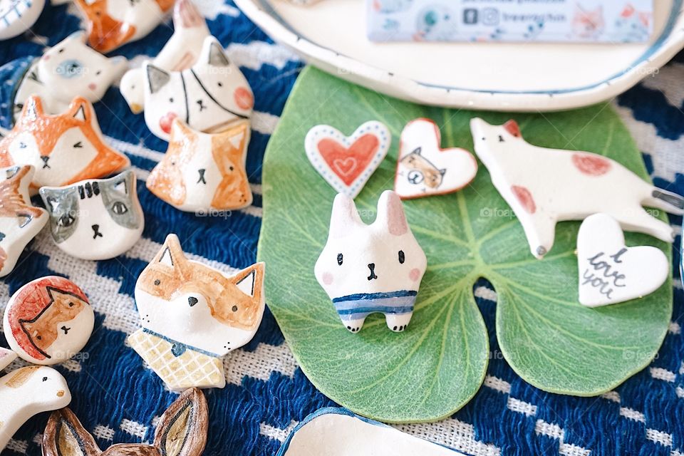 A top view photo of cute ceramic magnet in various shapes of adorable animals such as polar bear, cat, elephant, rabbit, penguin, fox and Chiba dog, selling at weekend market.