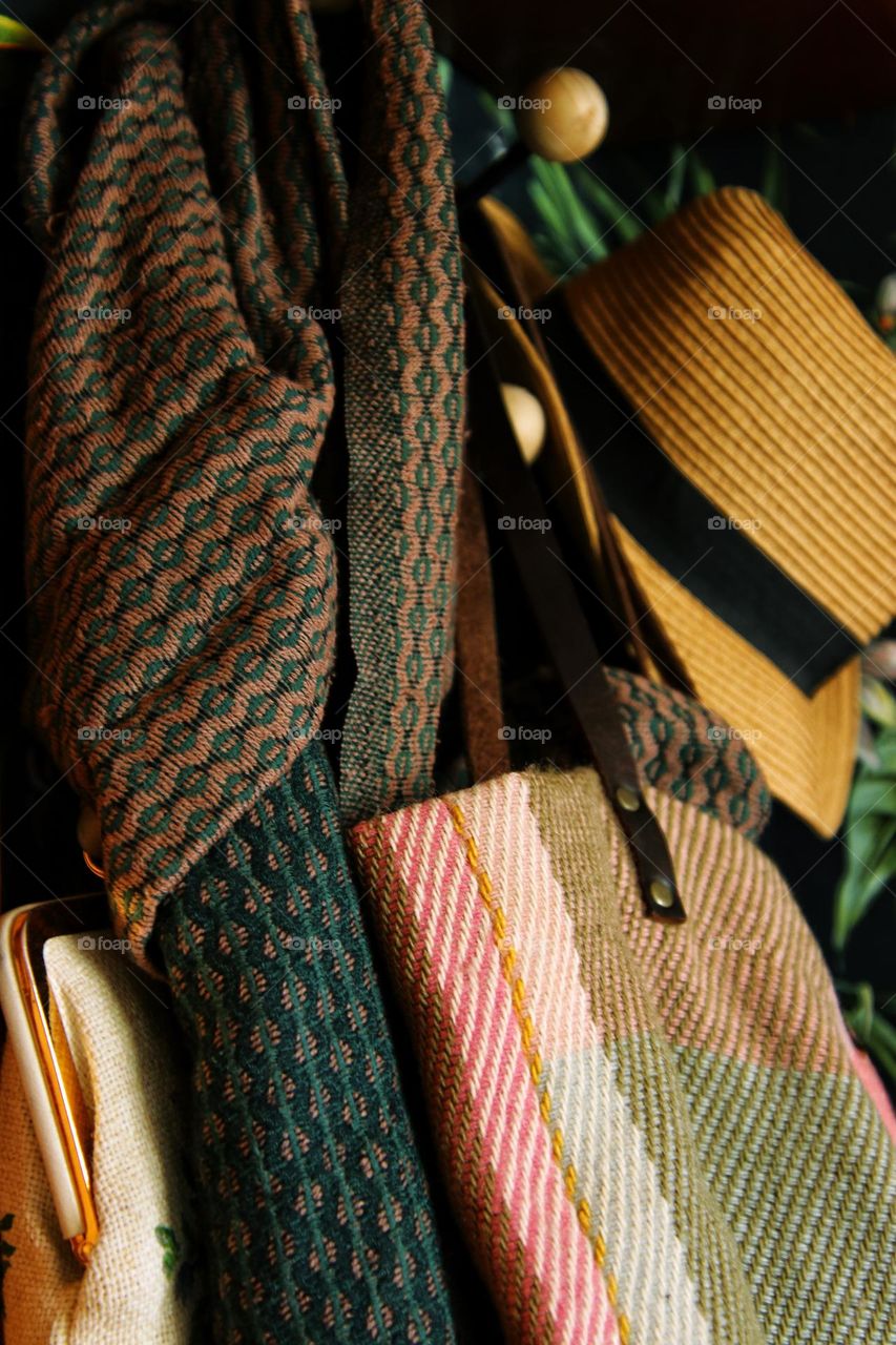 Close-up of colorful woolen scarves, bags and a straw hat on a wardrobe