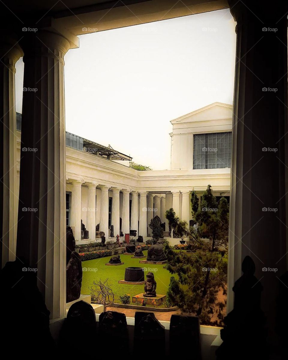 Portrait of a beautiful inner garden with statues, surrounded by white buildings with large columns