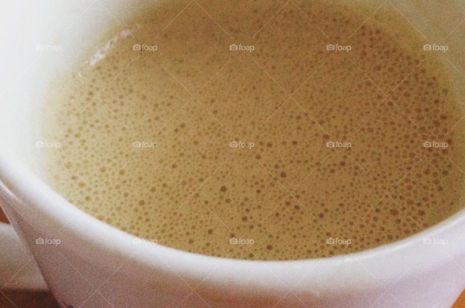 Close up shot of blended bulletproof coffee. Frothy and foamy in a white mug.  Coffee with butter and coconut oil. 