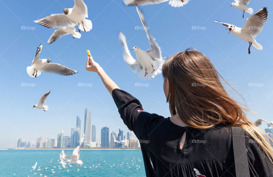 Young woman feeding seagulls, freedom concept