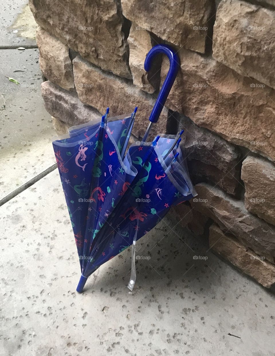 Umbrella by the cobblestone wall keeping dry form the rain on a springtime day. USA, America 