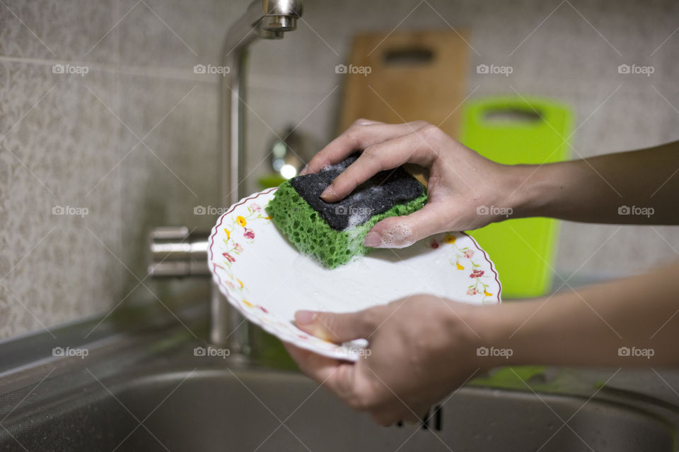 Woman's hands washing up the white plate. Every day house work concept