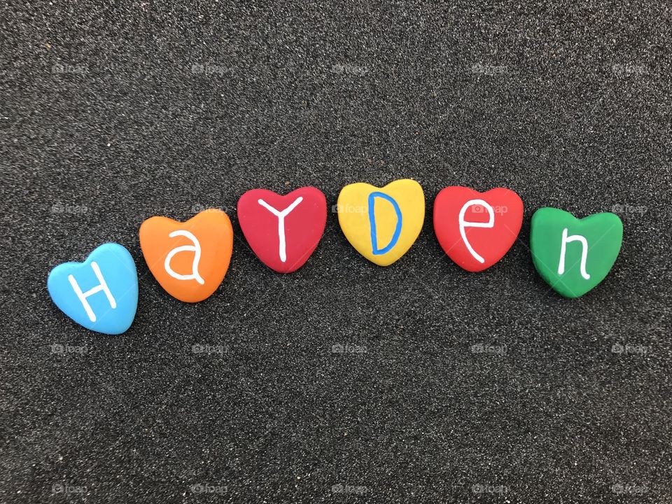 Hayden, female and male given name with colored heart stones over black volcanic sand