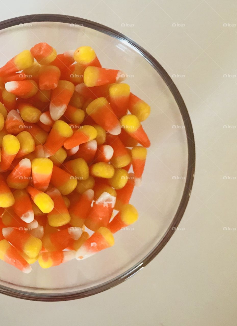 Sweet treat for Halloween. Delicious and Tasty candy corn in a clear glass bowl. 