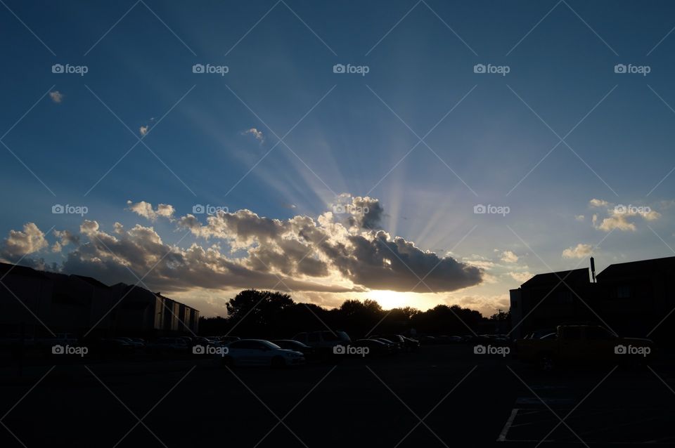 Suns rays shooting through a cloud over an apartment complex 