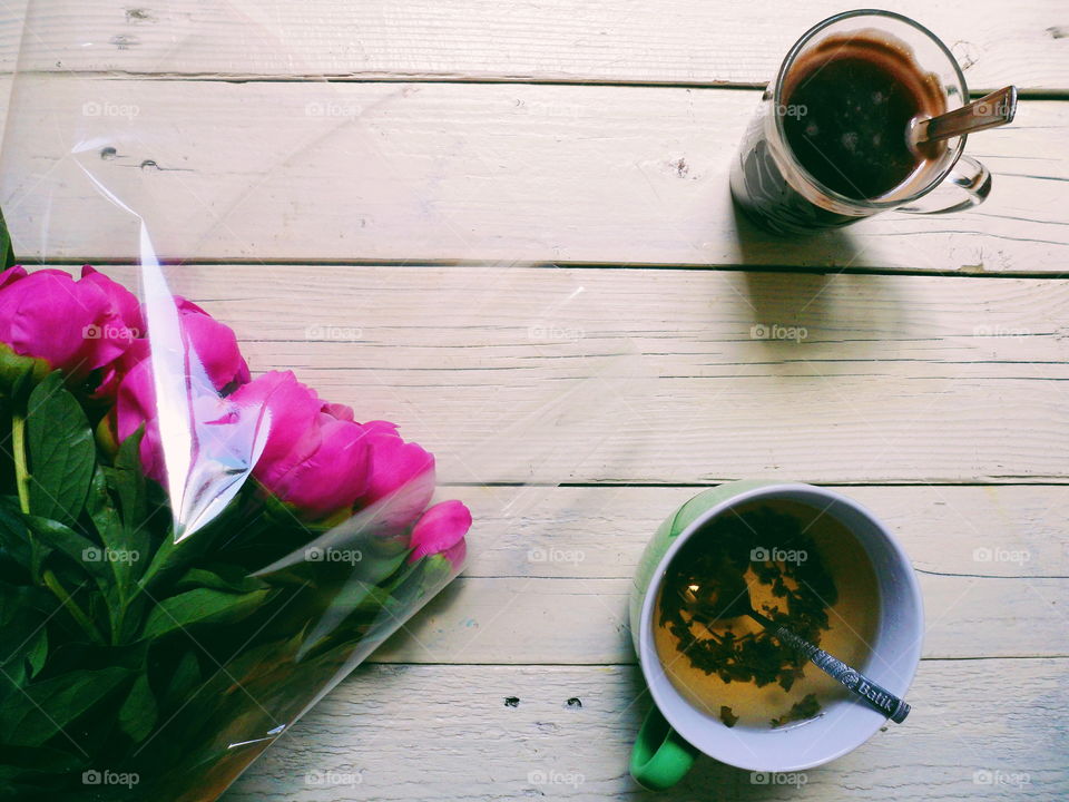 pink peony flowers, a cup of tea and a cup of coffee on white boards