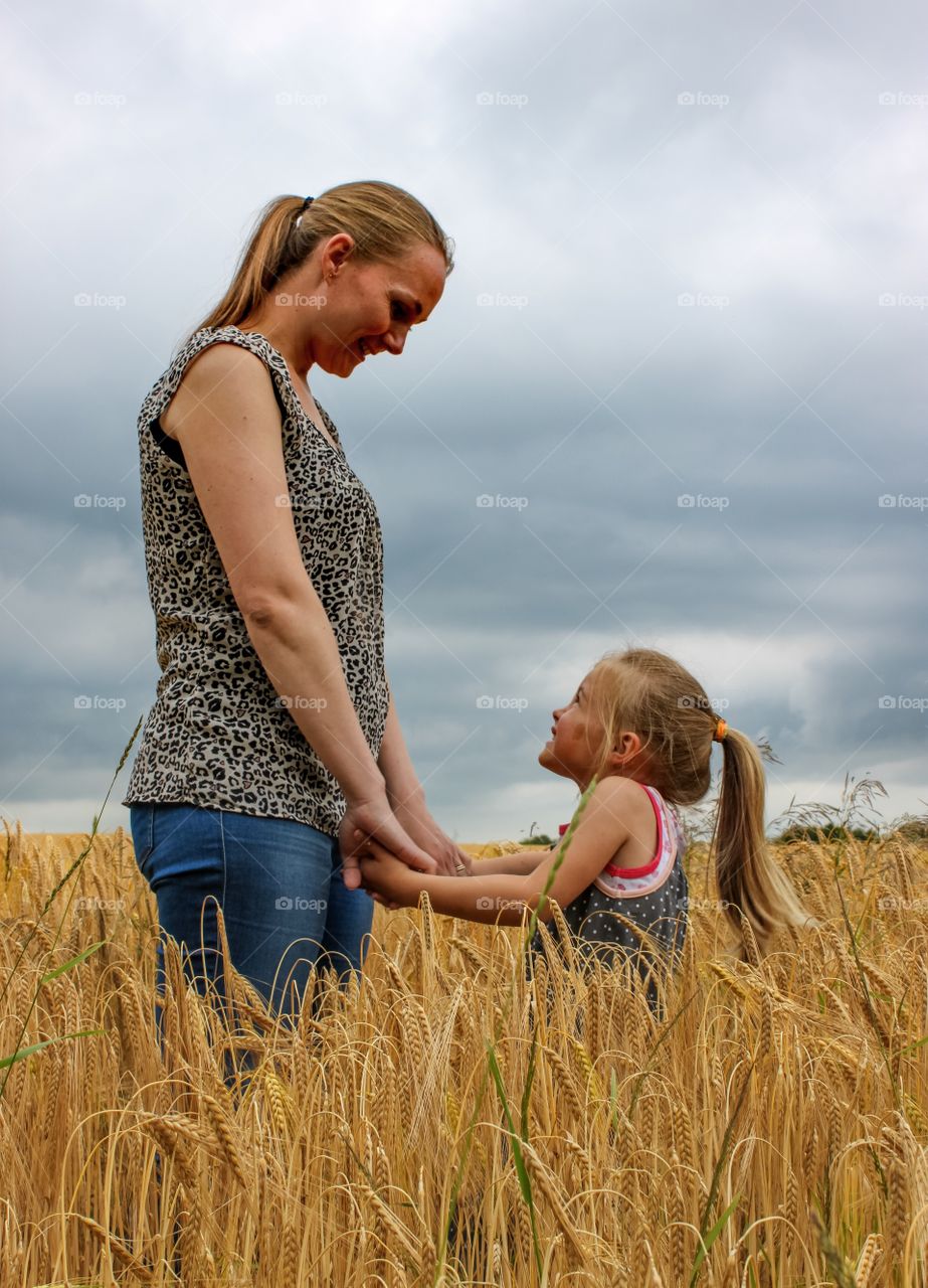 Mother and daughter standing in wheat field