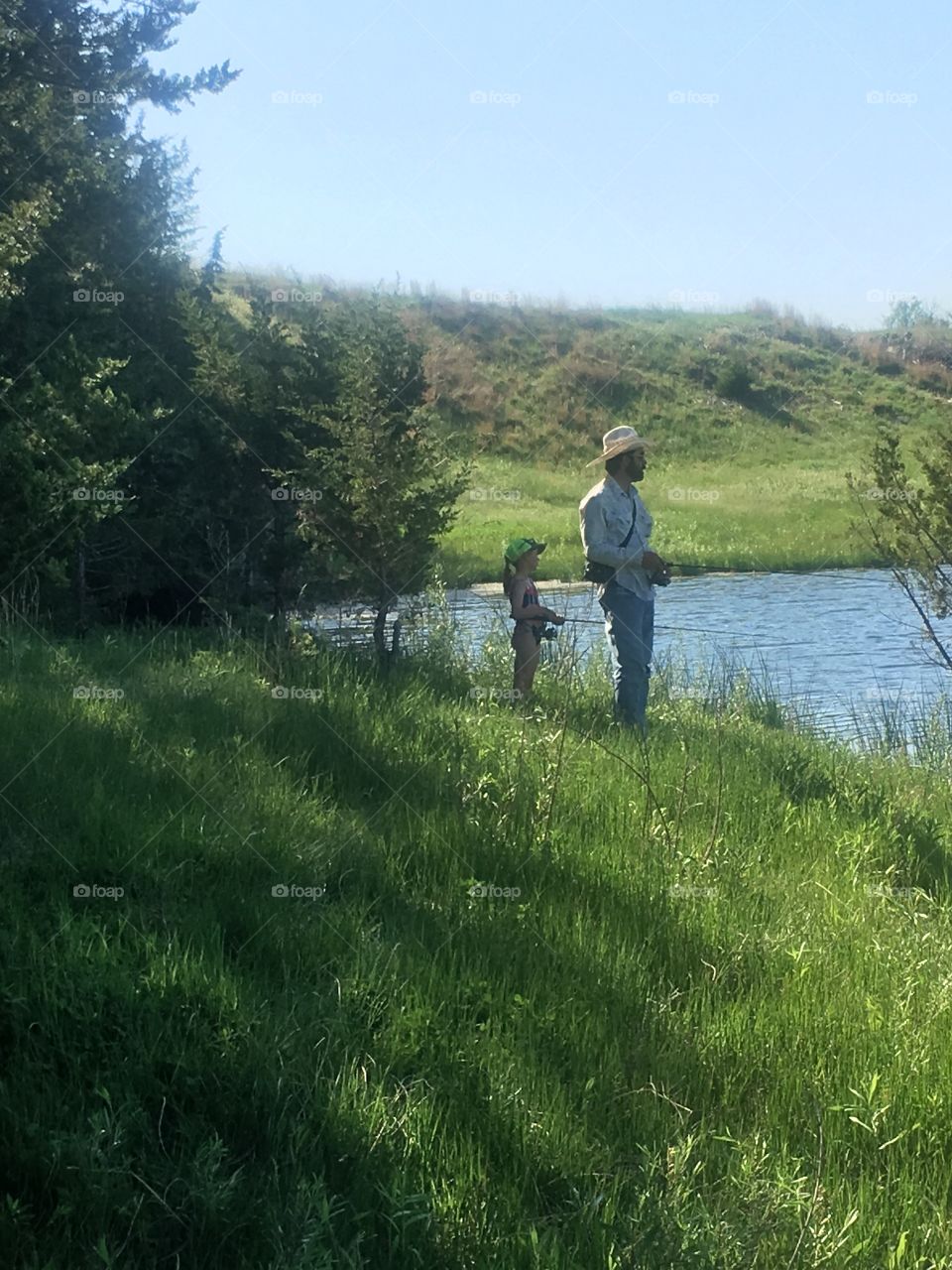 Father and daughter spending quality time together outside at their favorite fishing pond.