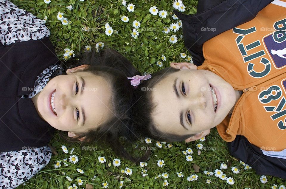 Siblings lying on the grass and laughing 