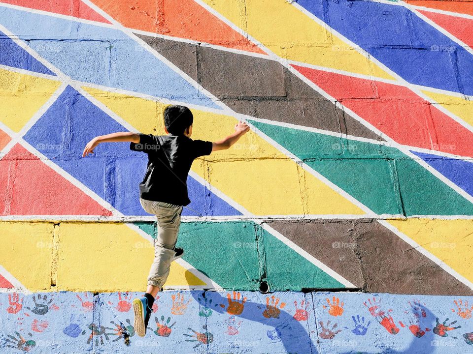 A boy running up a painted wall art in the city