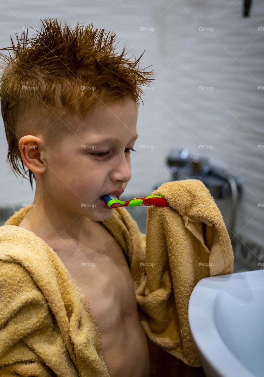 red-haired boy brushes his teeth in the bath, personal hygiene.