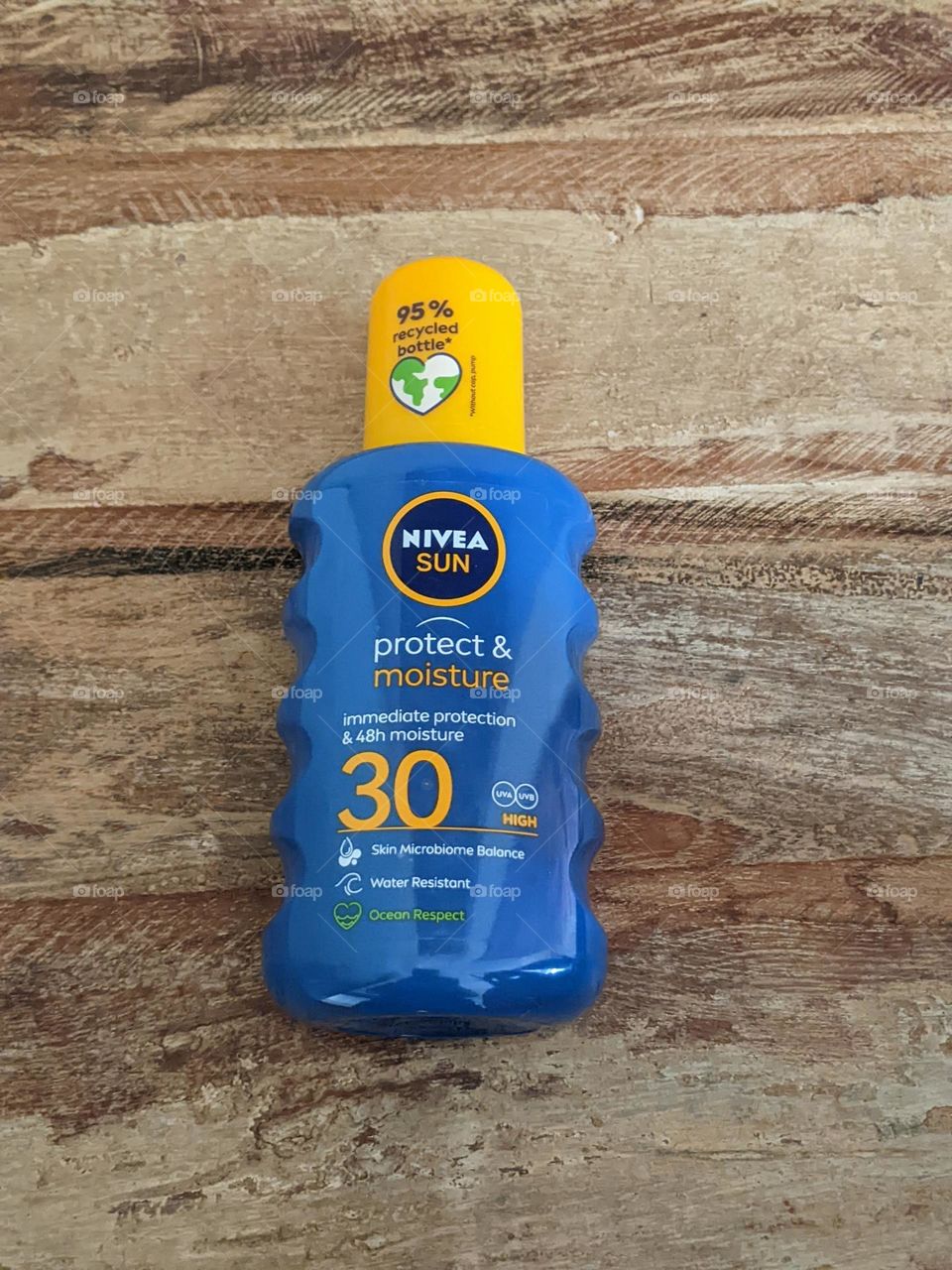 Blue and yellow bottle of spray-on sunscreen on a wooden table. Skincare for the summer (and the rest of the seasons)