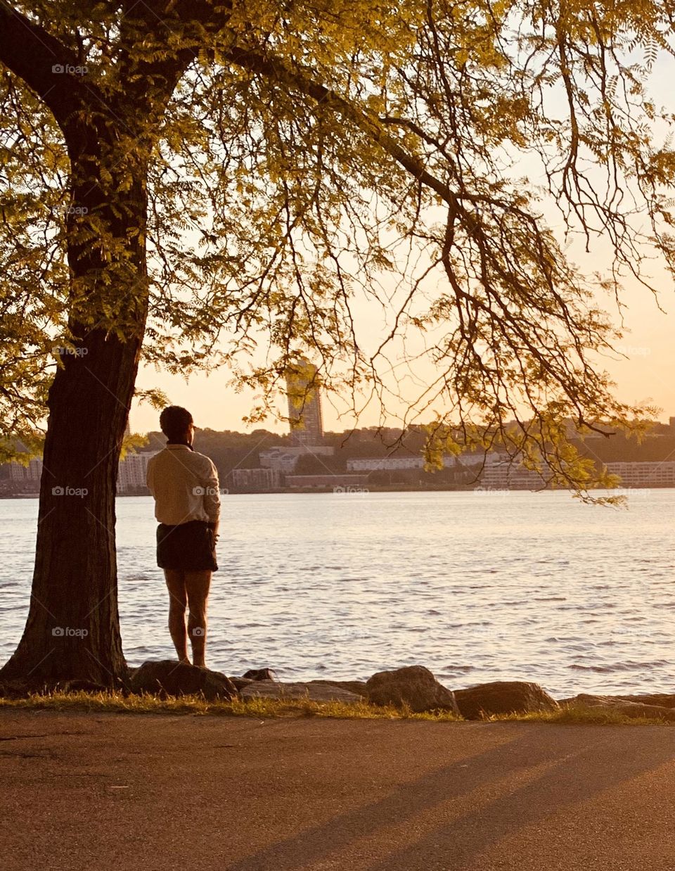 Woman thinking under a tree facing the river