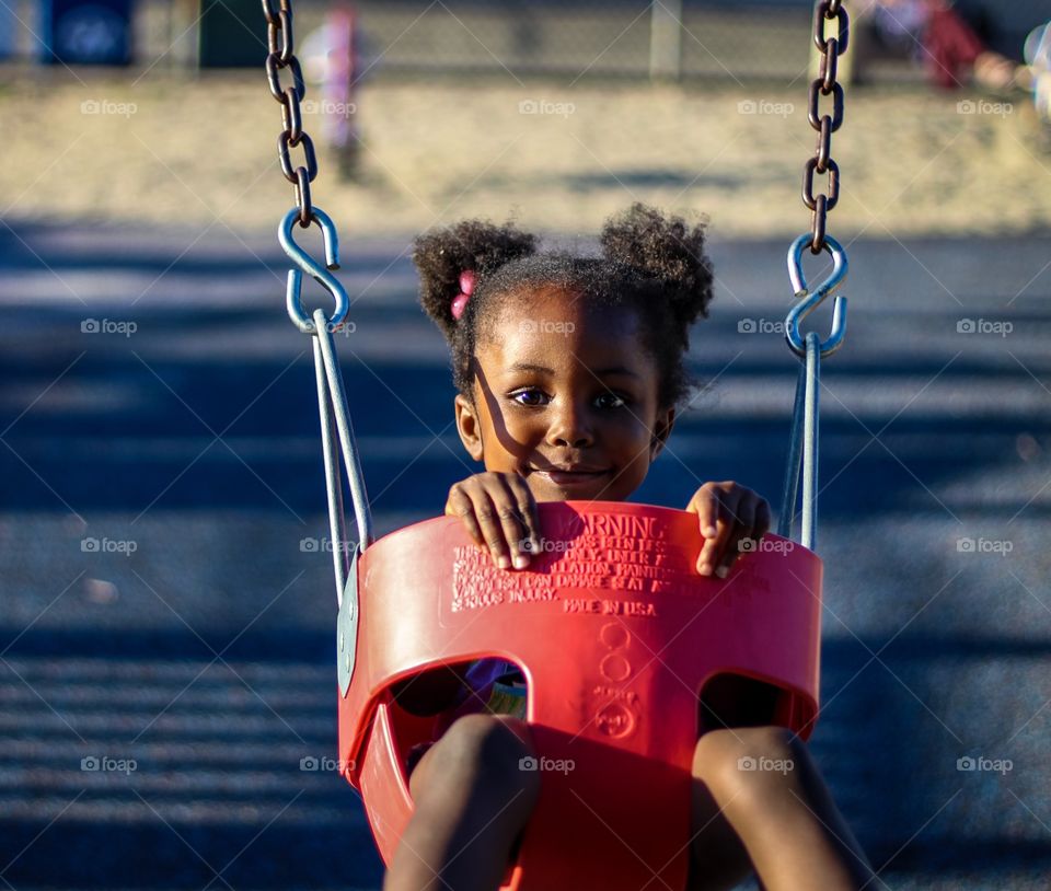 A little girl having fun at the park on the swing