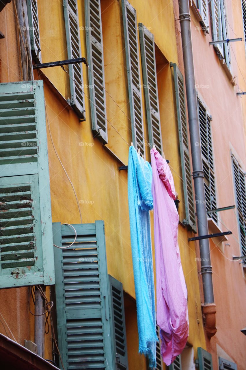 In old part of town colourful buildings and sheets in pink and blue hanging out of a window 